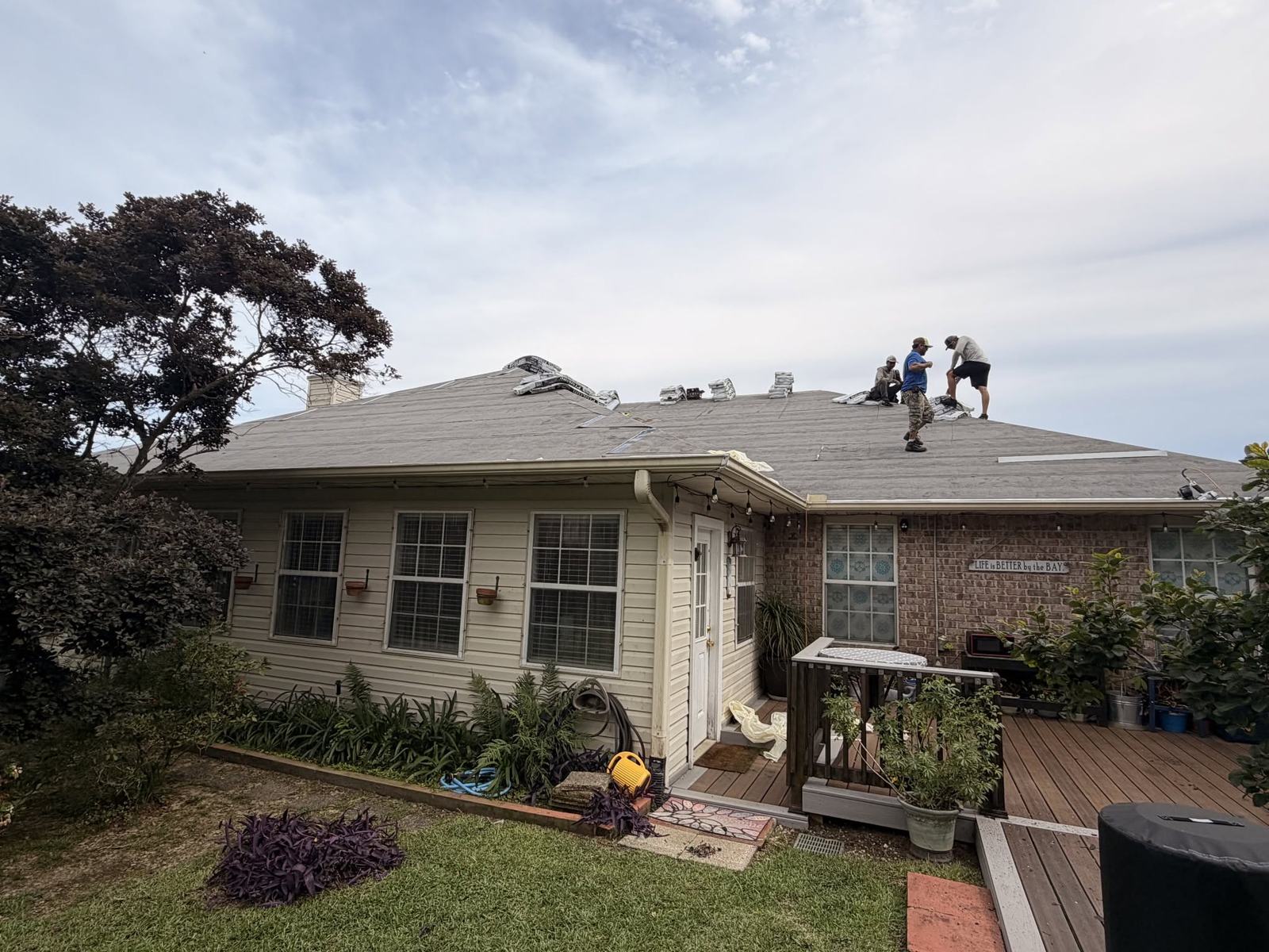 Roofing crew laying shingles on a brick home